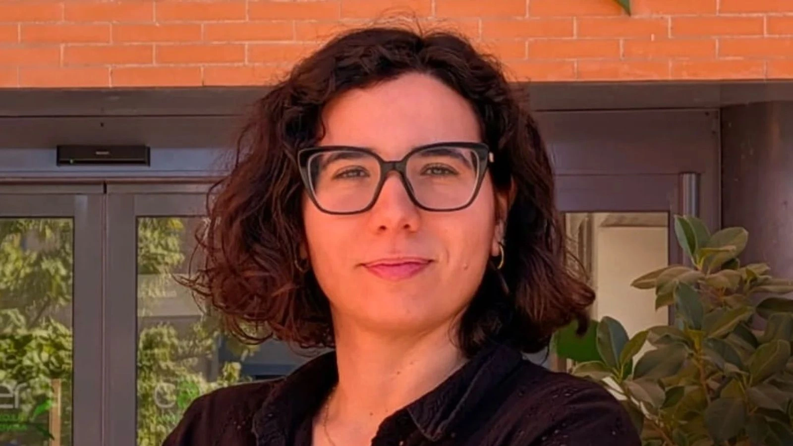 La investigadora abaranera Cristina Molina López, con gafas y camisa oscura, ante la entrada del CABIMER en Sevilla.