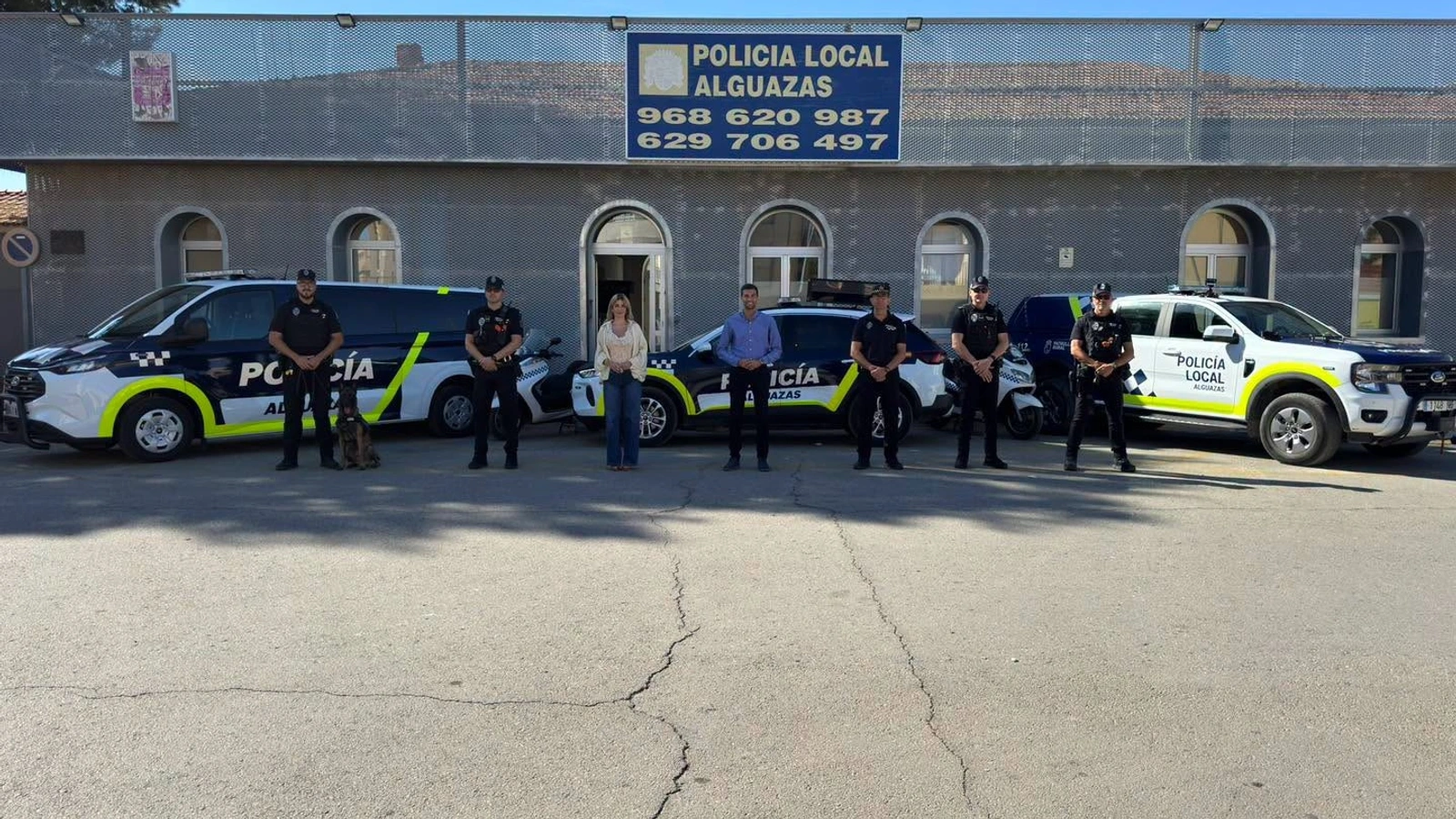 Agentes de la Policía Local de Alguazas, el alcalde y la concejala de Seguridad posan ante la sede policial junto al nuevo furgón, otros dos coches patrulla y el perro de la unidad canina