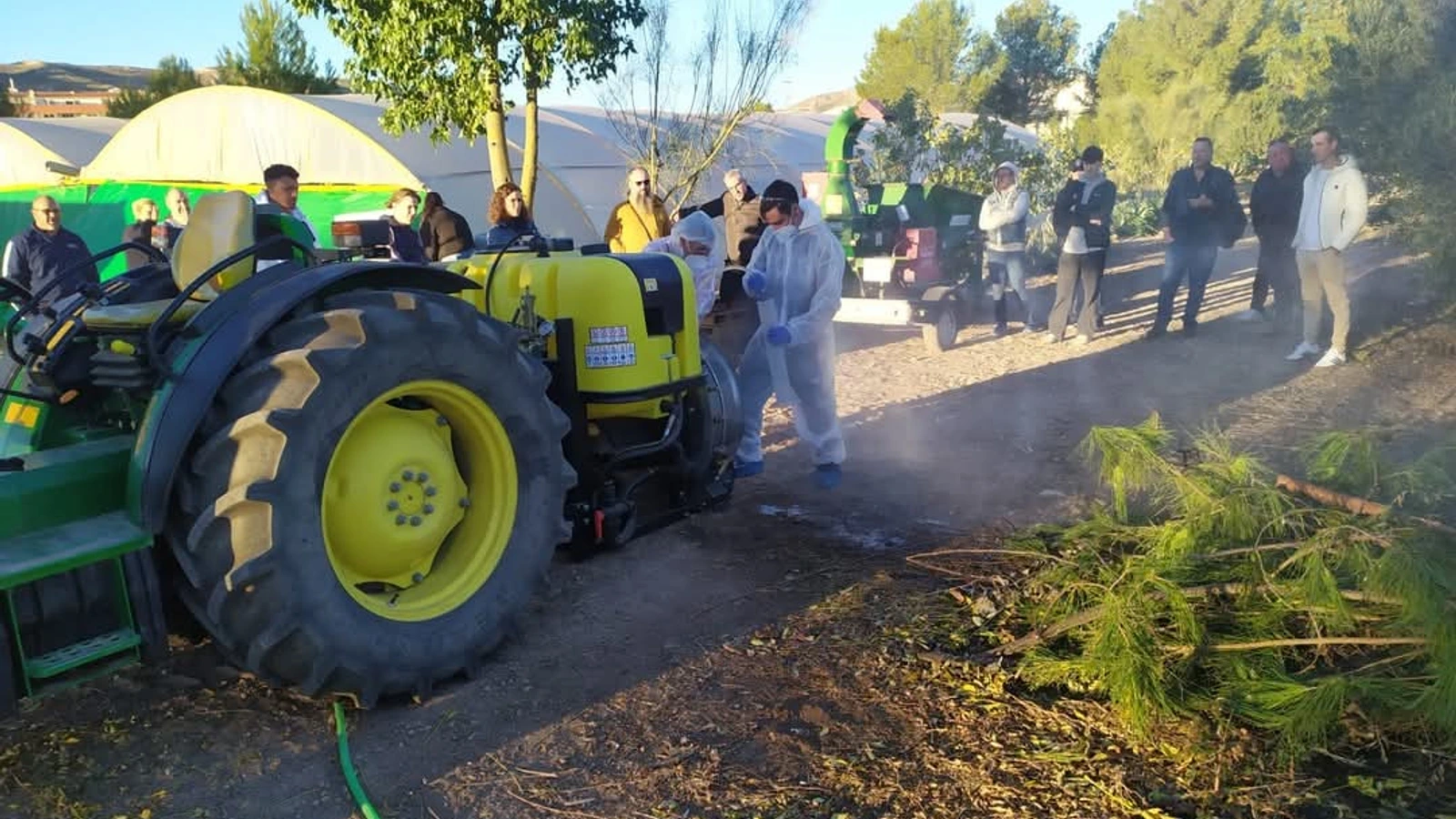 Participantes en una práctica de formación agrícola junto a un tractor y un equipo de aplicación