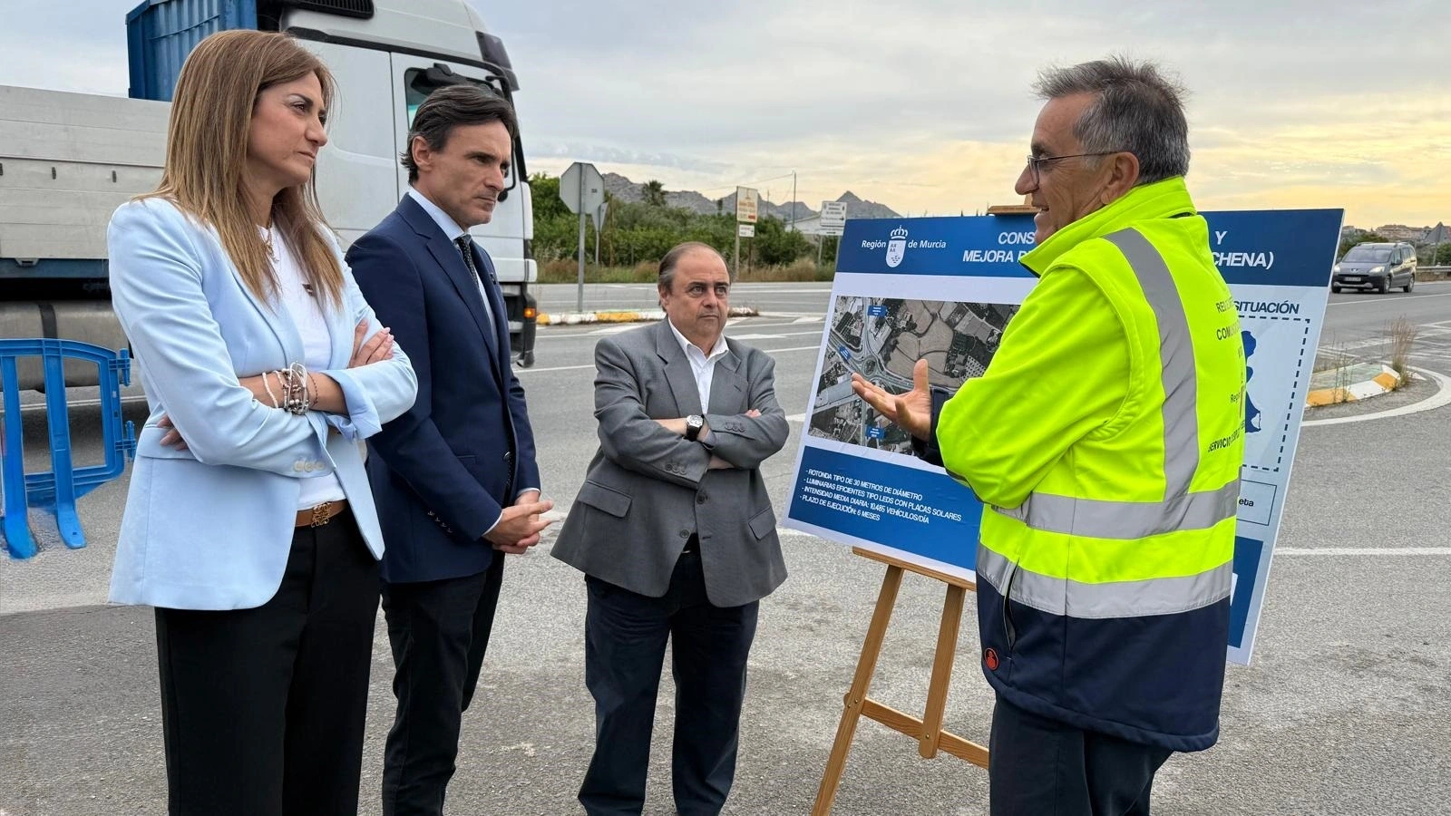Responsables autonómicos y municipales escuchan a un técnico junto al panel del proyecto de glorieta en el cruce de la RM-554, en Archena.