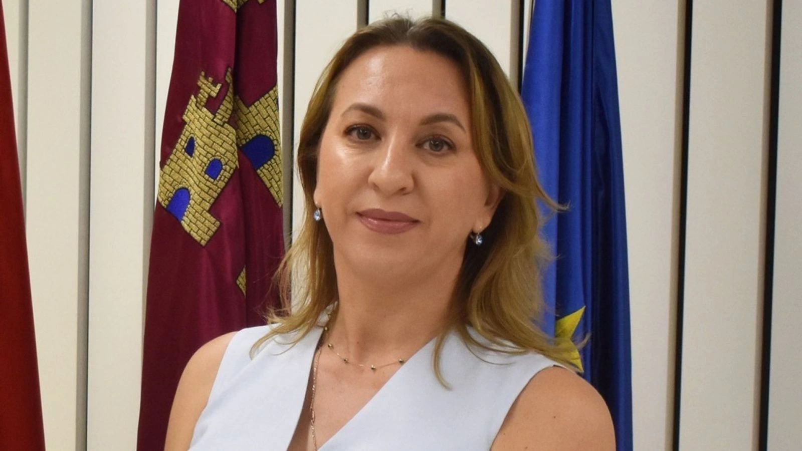 Retrato de la concejala Inga Popa ante las banderas de la Región de Murcia y de la Unión Europea.