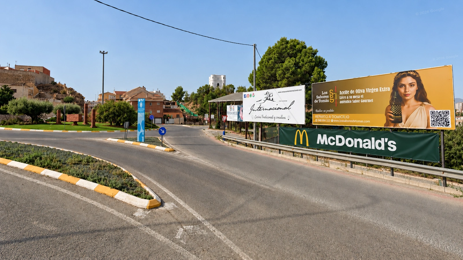 Montaje de una vista de la entrada de Archena con una franja verde de McDonald’s añadida digitalmente bajo los paneles publicitarios