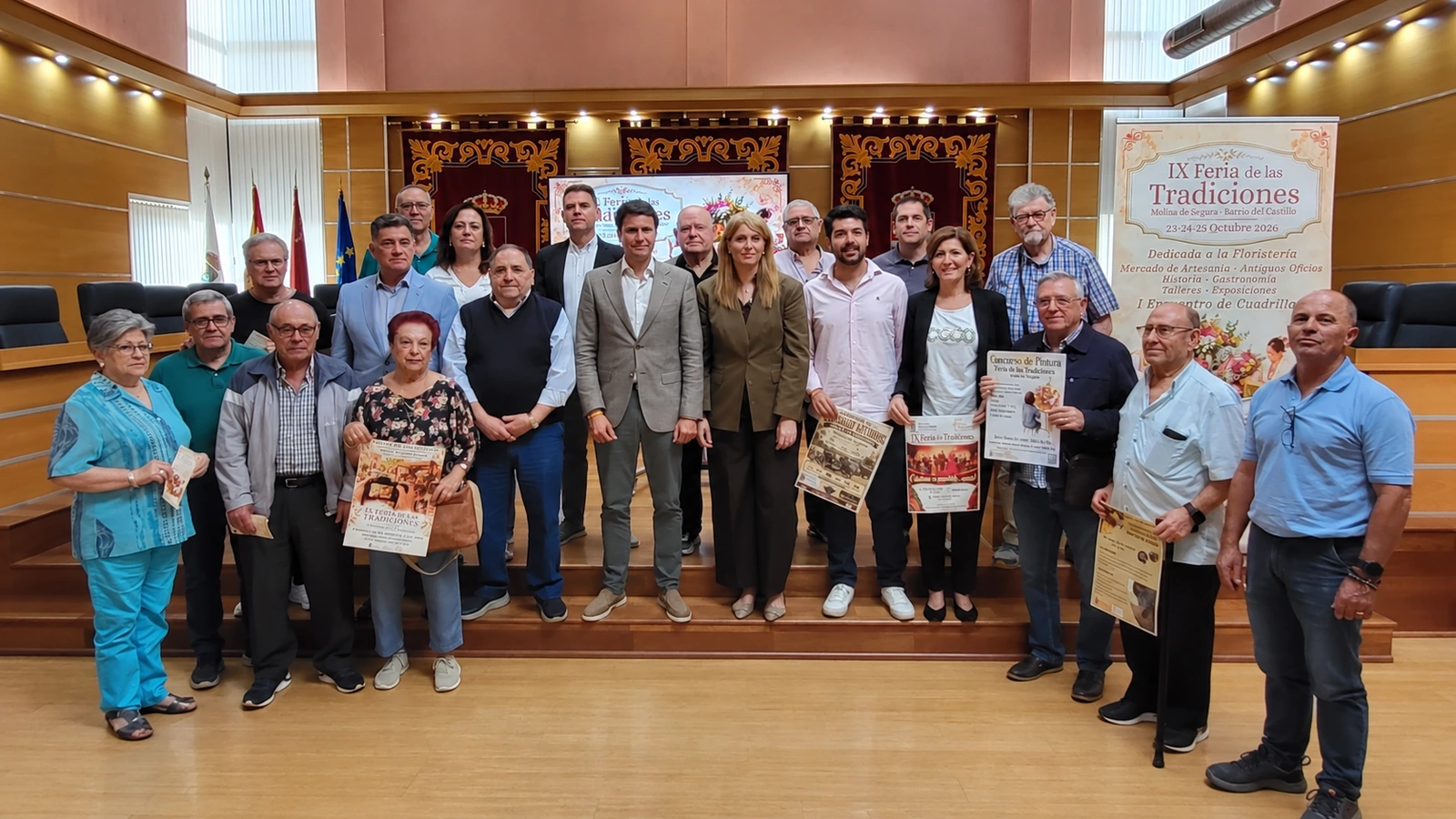 Participantes en la presentación de la Feria de las Tradiciones de Molina de Segura junto a los carteles de la edición de 2026
