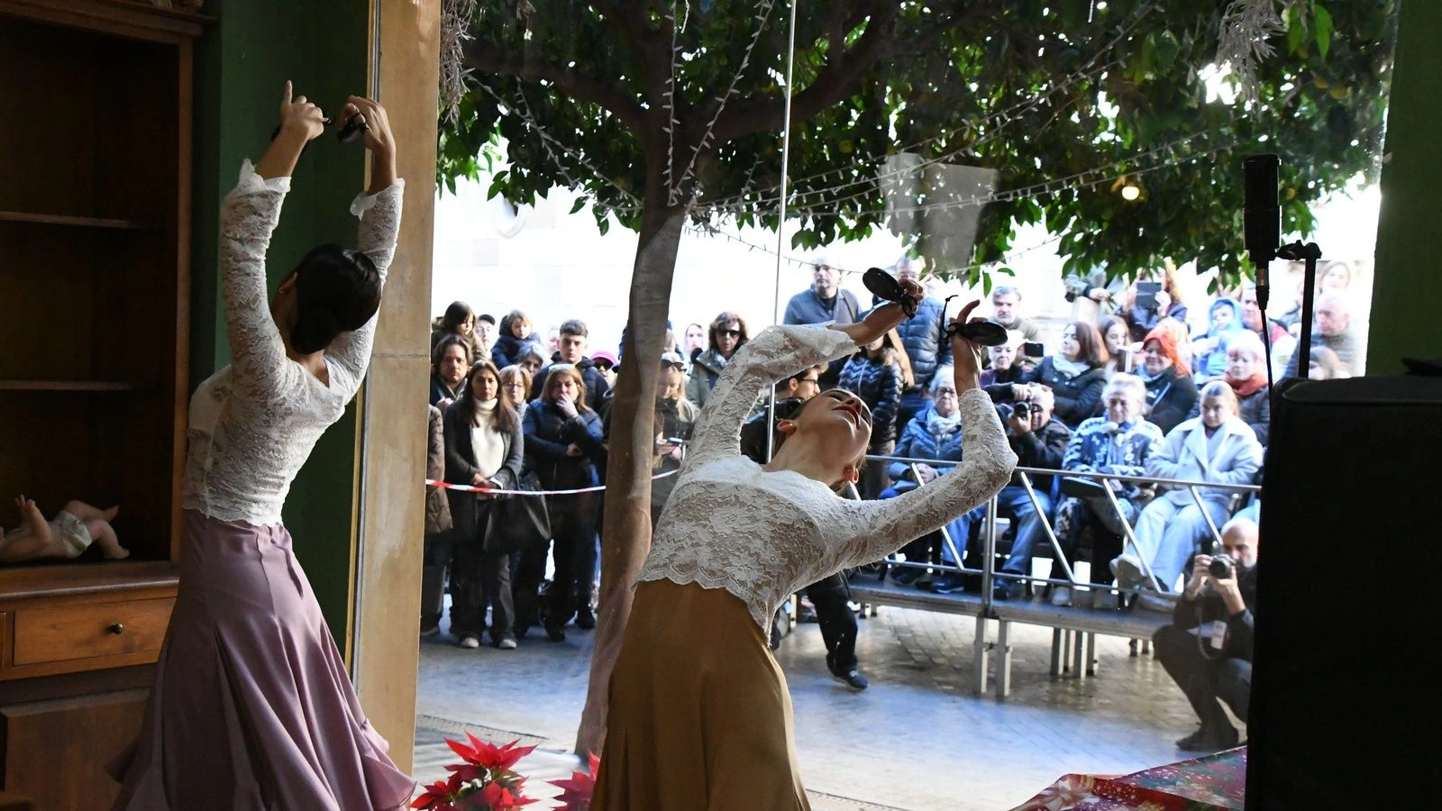 Dos bailarinas actúan dentro del escaparate de un comercio del centro de Murcia mientras el público las observa desde la calle.