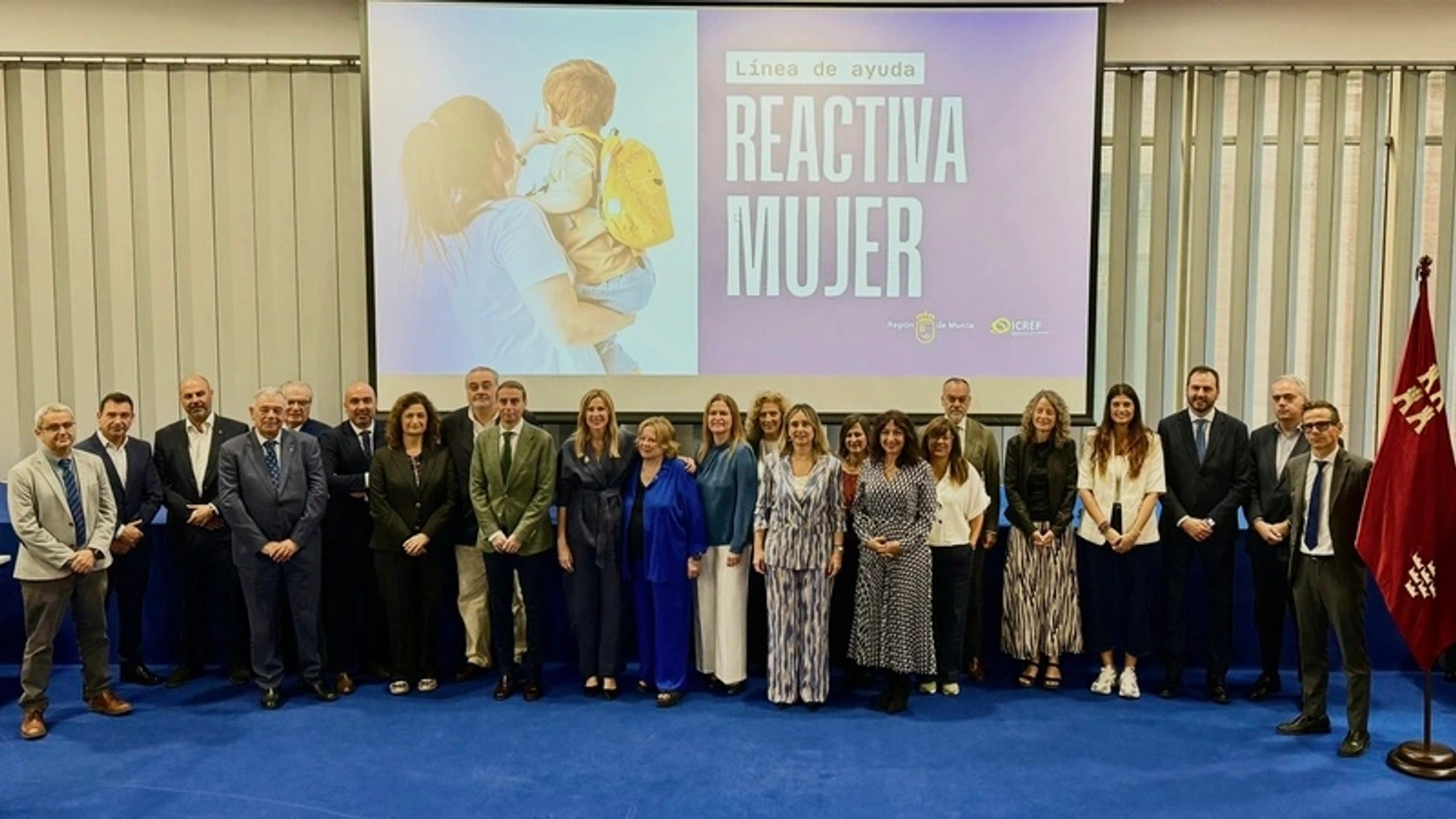 Participantes en la presentación de Reactiva Mujer ante una pantalla con el nombre del programa.