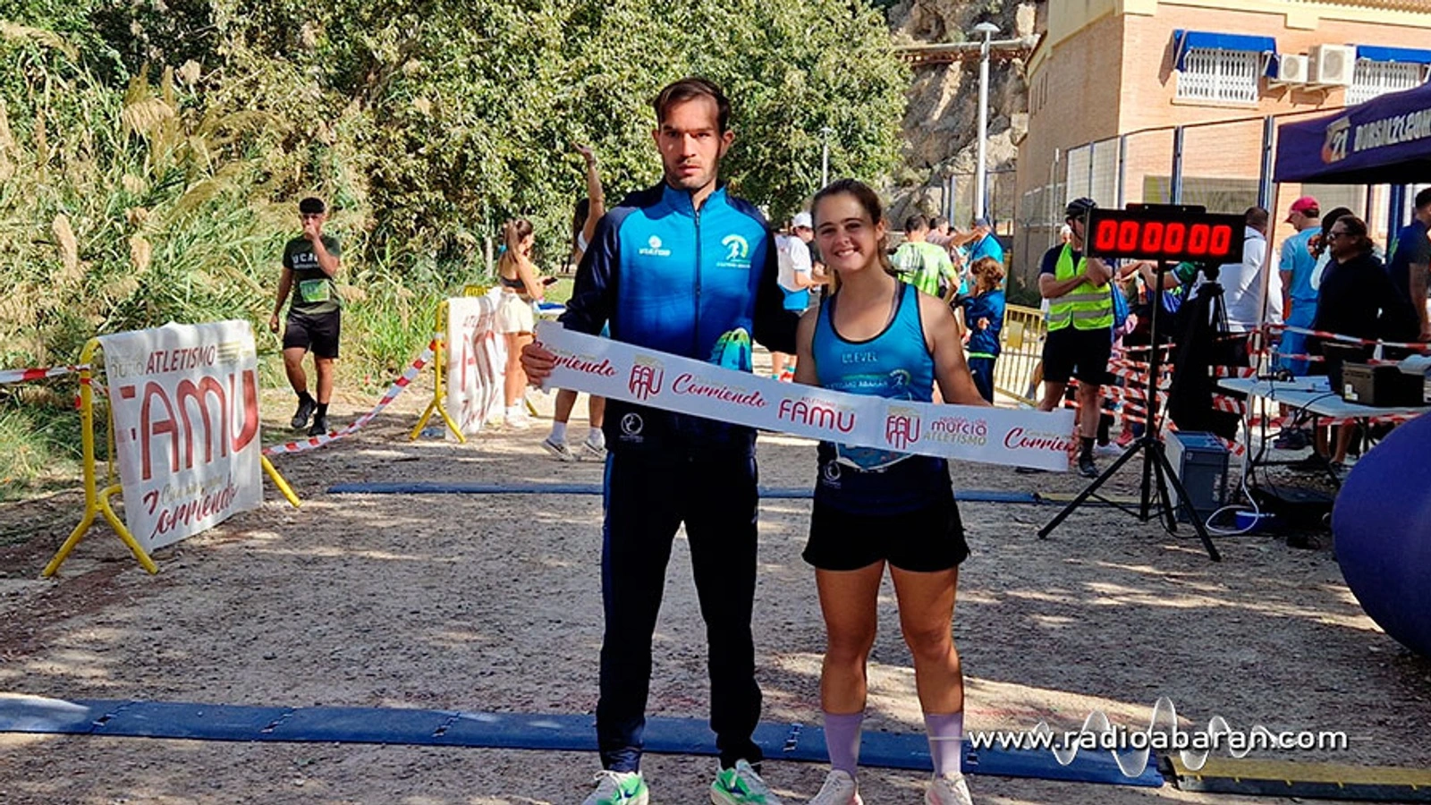 Raúl Martínez y Marina Pujalte posan con la cinta de meta de la FAMU en la llegada de la Ruta de las Norias en Abarán