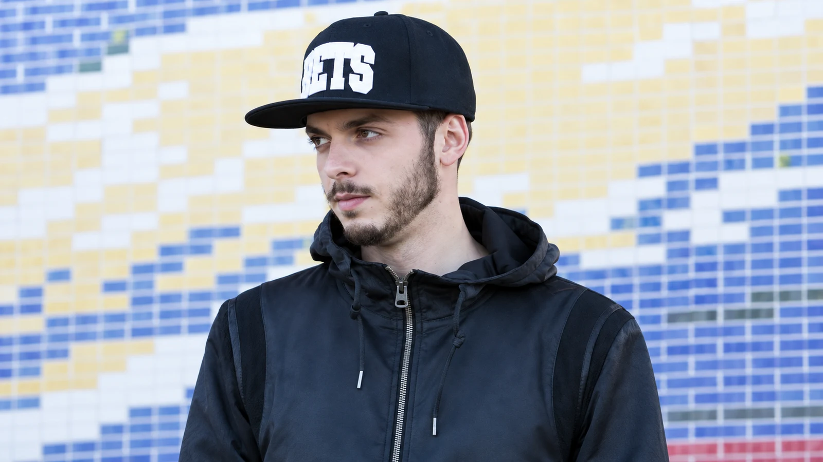 Surce Beats, productor musical vinculado a Archena, con gorra negra ante un fondo urbano.