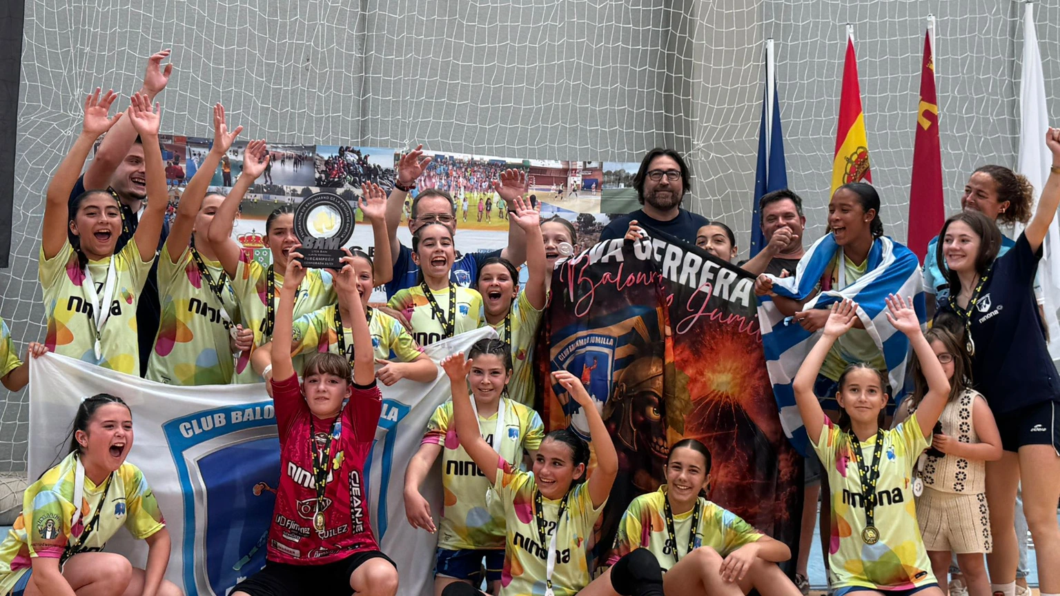 Cantera del Club Balonmano Jumilla celebrando en un pabellón.