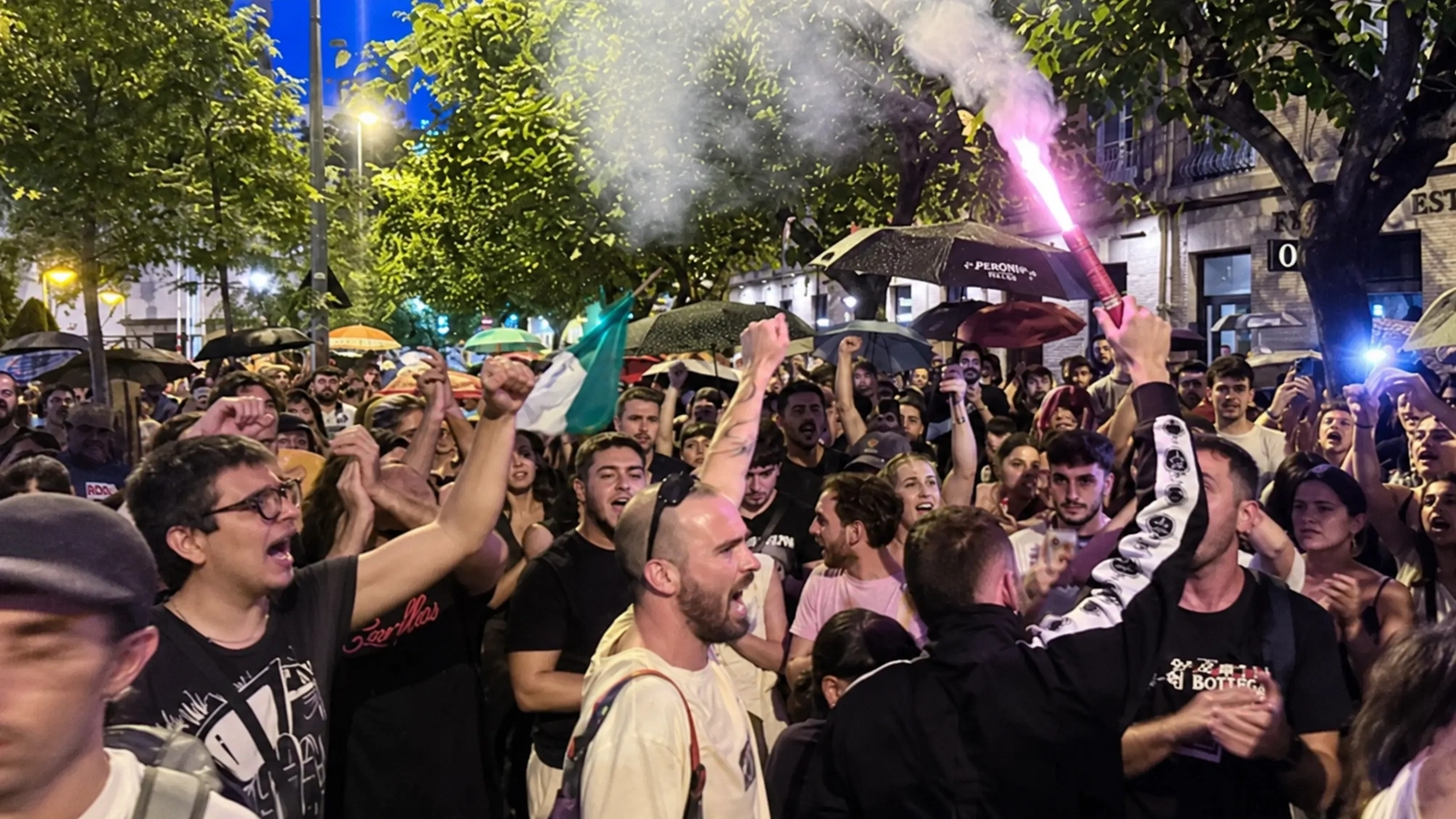 Participantes en la manifestación por la vivienda en Murcia, con los brazos alzados y una bengala.