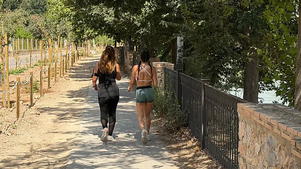 Dos chicas, caminando por el Paseo Ribereño a la sombra de unos árboles. C. C. Búsqueda vi