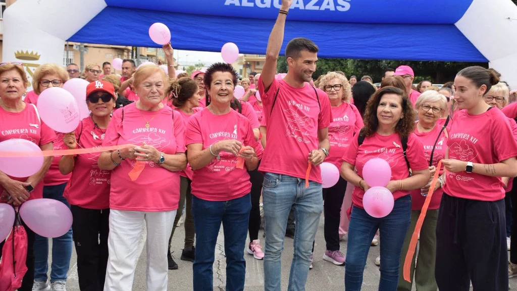 Participantes con camisetas rosas en la salida de la XII Marcha contra el Cáncer de Alguazas, bajo el arco del Ayuntamiento