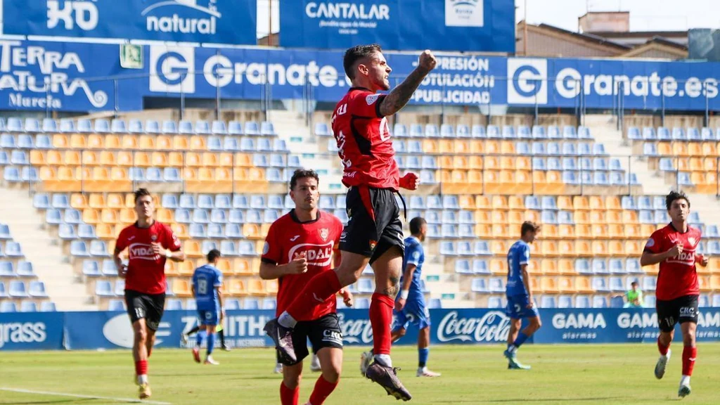 Un jugador del CD Cieza celebra un gol saltando con el puño en alto en La Condomina