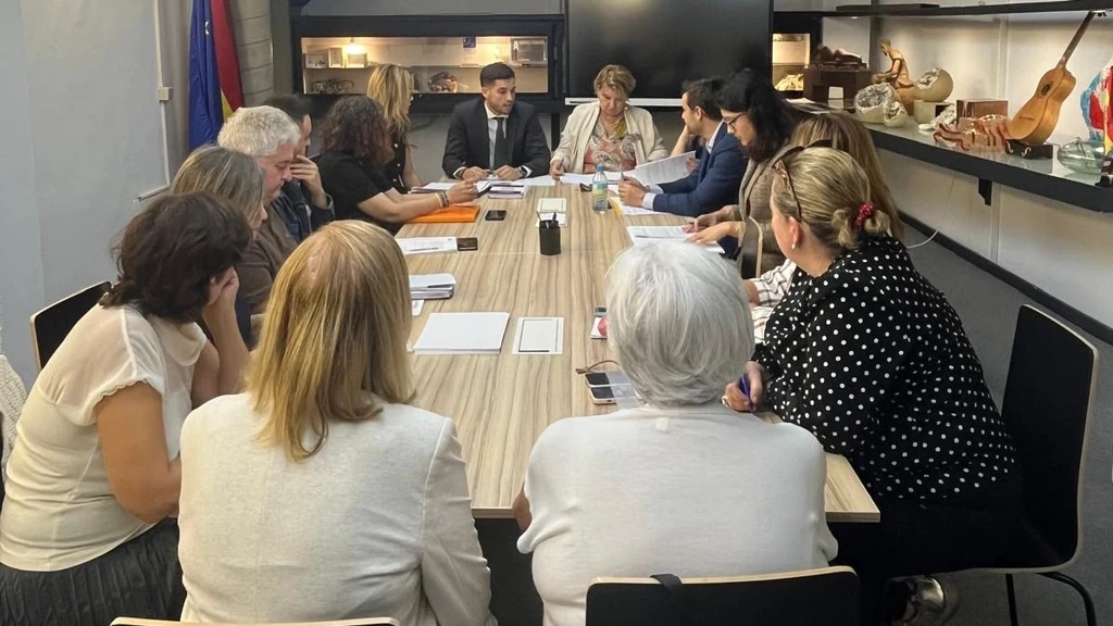 Reunión en torno a una mesa en la imagen institucional que acompaña la convocatoria de ayudas a las organizaciones de consumidores